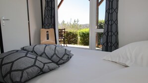 A bedroom with a bed, pillows, a guitar, and a view of the outdoors.