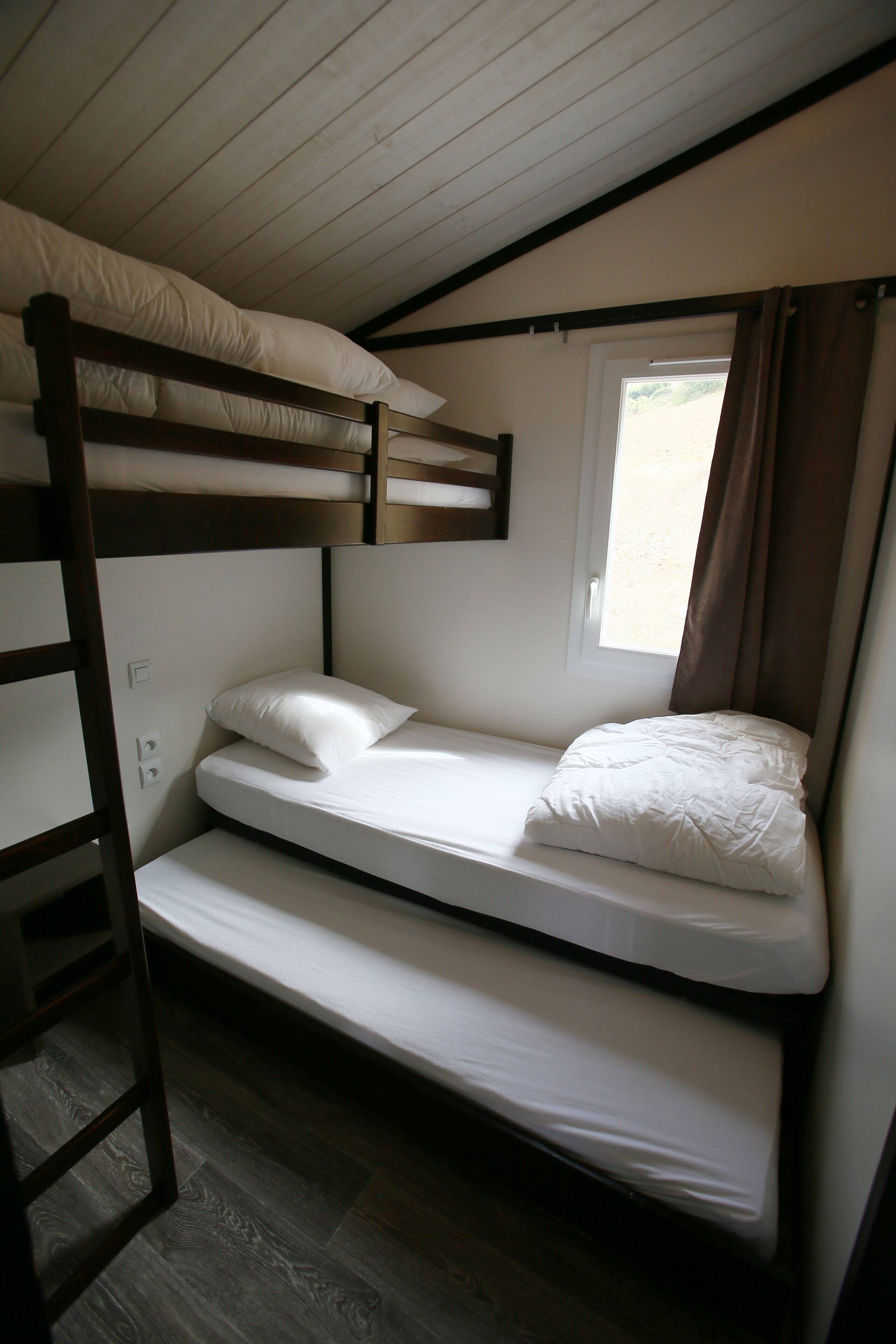 Une chambre avec un lit superposé, une fenêtre et des rideaux.