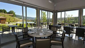A restaurant with outdoor seating, large windows, and a view of the countryside.