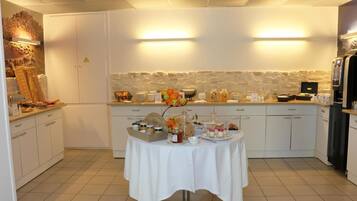 A modern kitchen with white cabinets, a stone backsplash, and a buffet table with various food items and condiments.