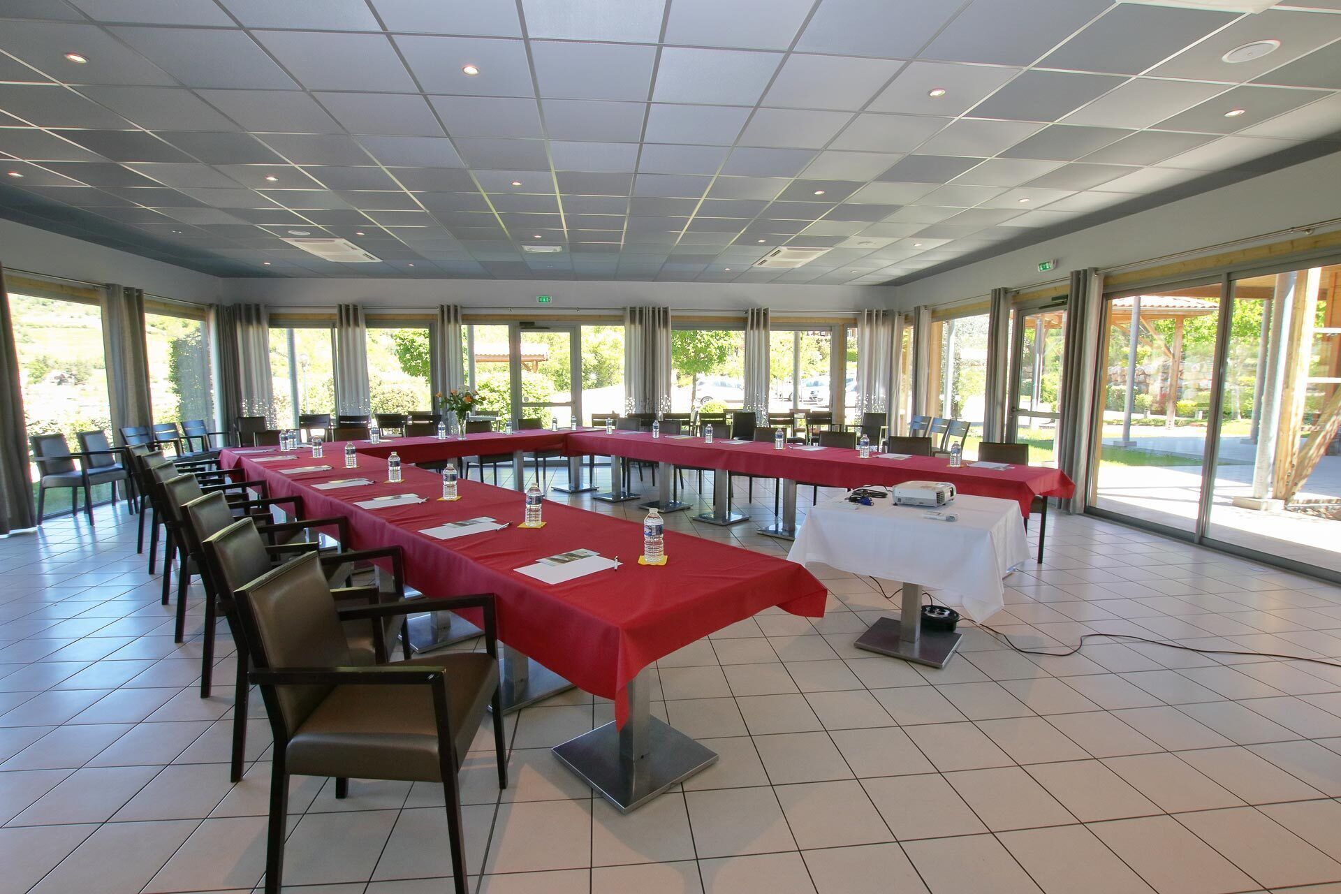 Un salón de conferencias con varias mesas, sillas y un proyector.