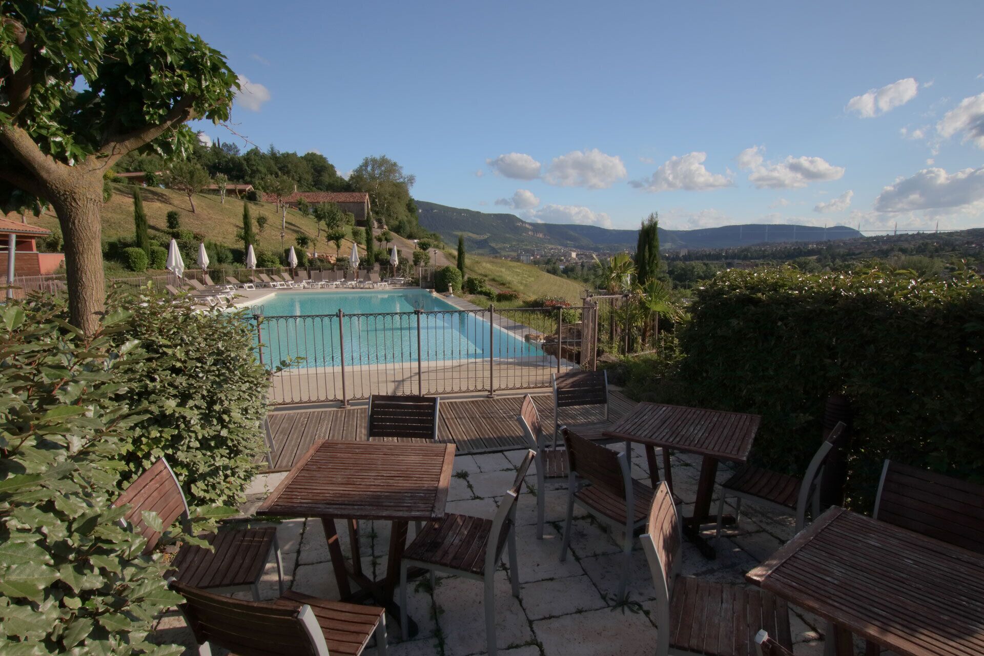 A pool area with wooden deck seating and a view of the landscape.