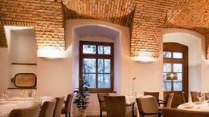 Um restaurante com paredes de tijolo, teto de madeira e uma área de jantar central com mesas e cadeiras.