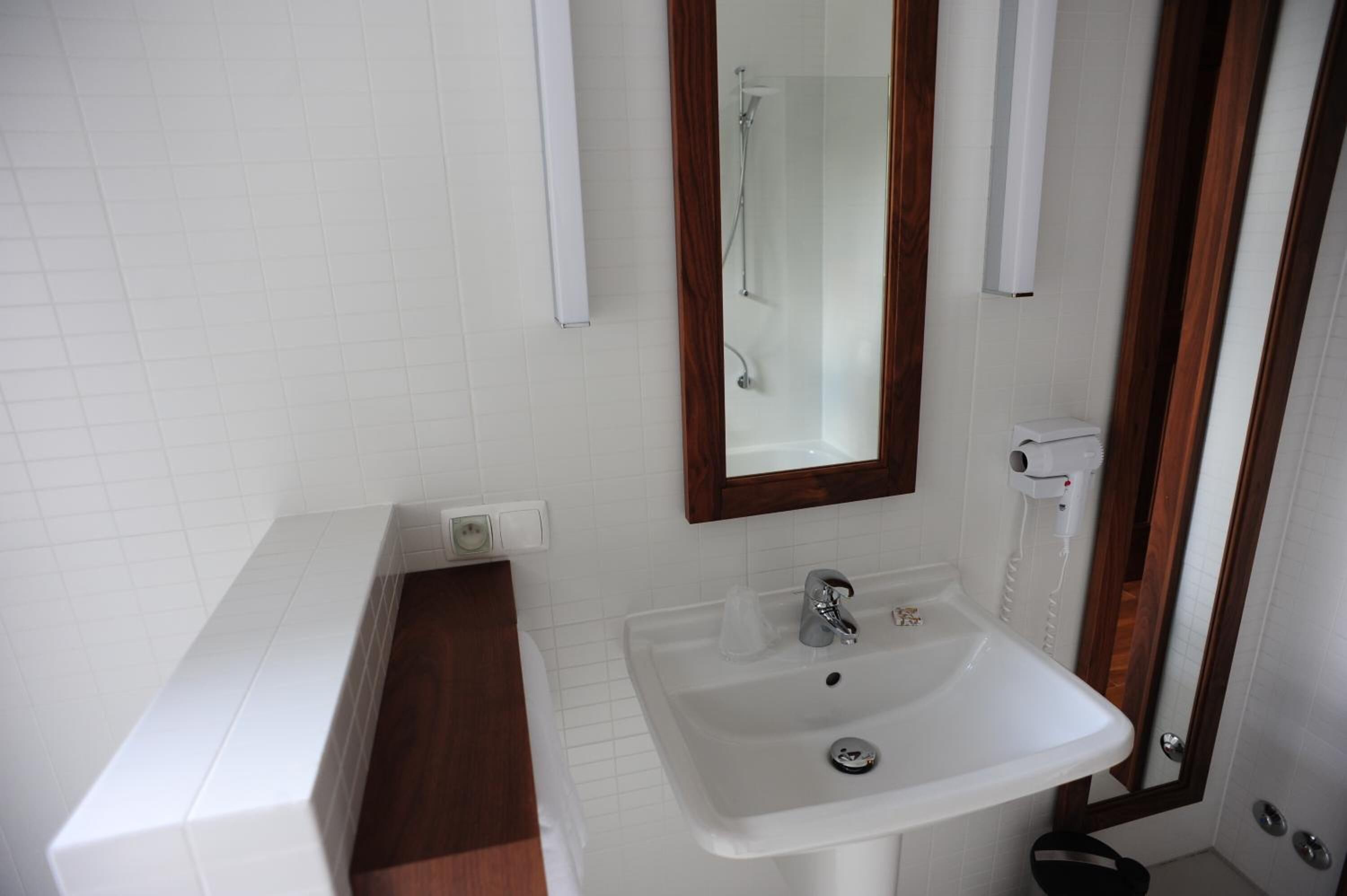 A bathroom with a white sink, a mirror, and a shower.