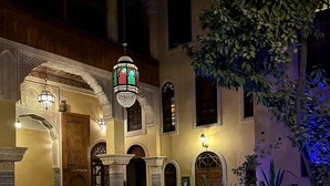 A courtyard with a pool, ornate arches, and traditional lighting fixtures.