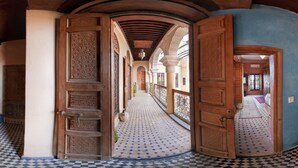 A corridor with ornate wooden doors and patterned tile flooring.
