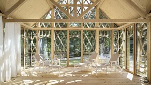 A covered outdoor seating area with wooden beams and large windows.