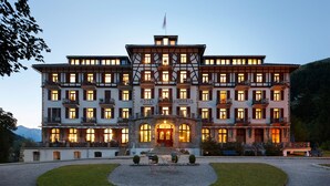 A large, multi-story hotel with a prominent entrance and a well-maintained garden in front.