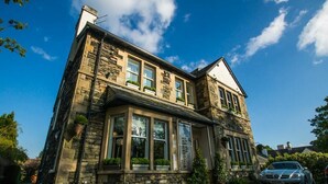 A stone building with large windows and a car parked in front. - Windermere Suites (Windermere)