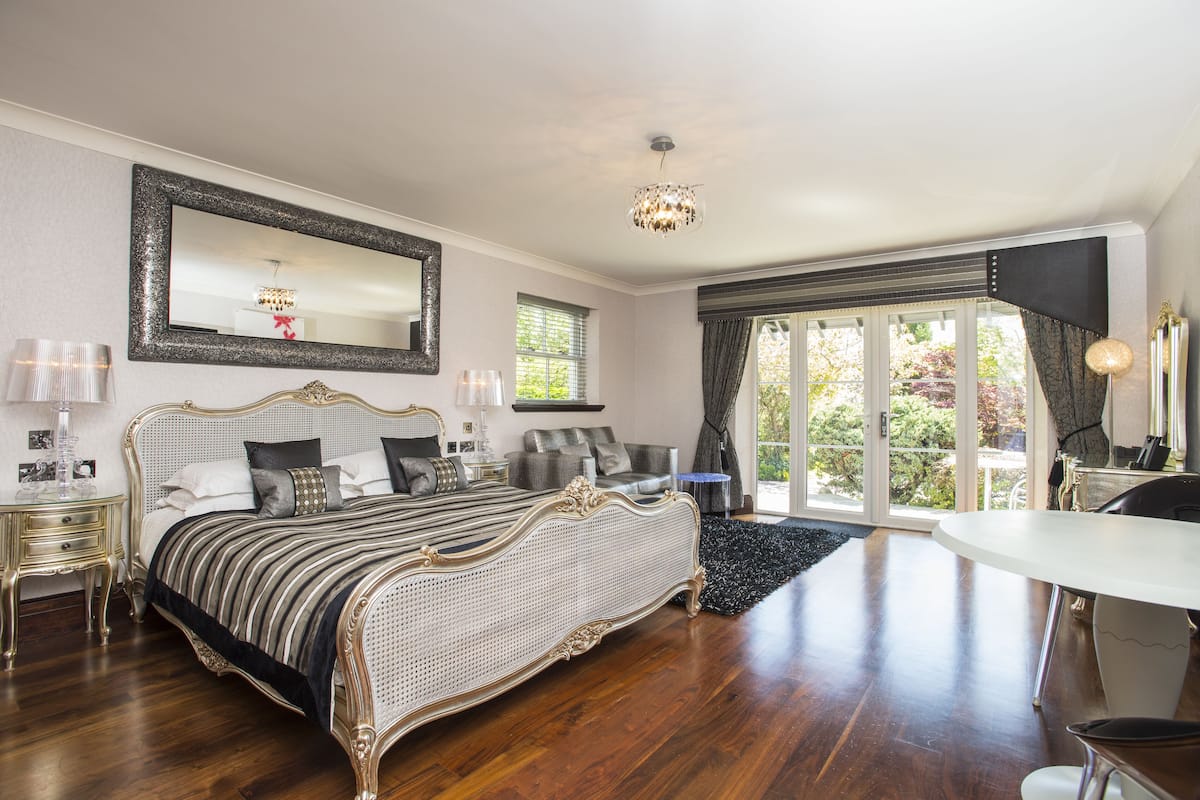 A spacious bedroom with a large bed, a dining table, and a balcony with a view.