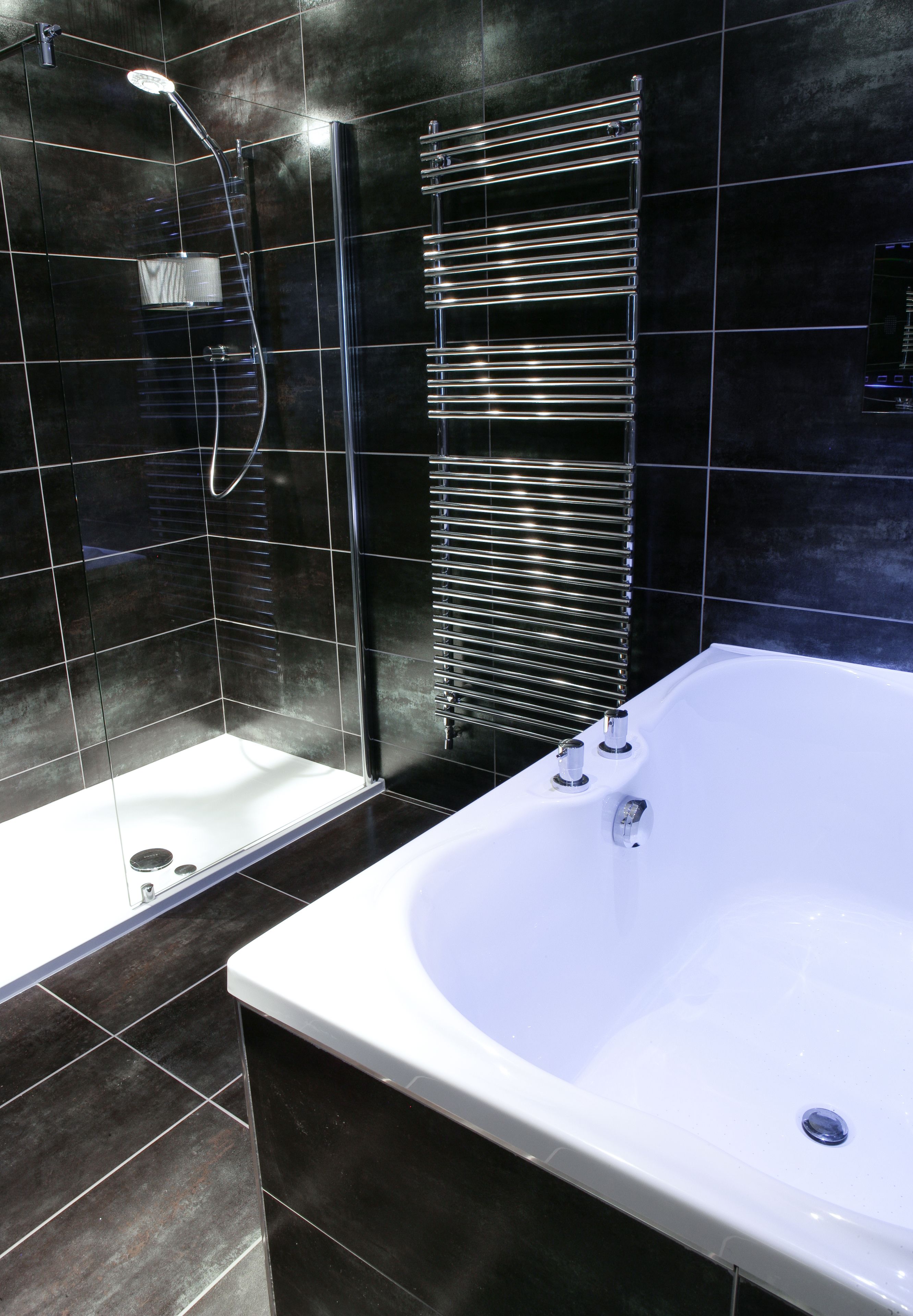 Un baño moderno con ducha de vidrio, una bañera independiente y un perchero de pared.