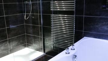 A modern bathroom with a glass-enclosed shower, a standalone bathtub, and a wall-mounted towel rack.
