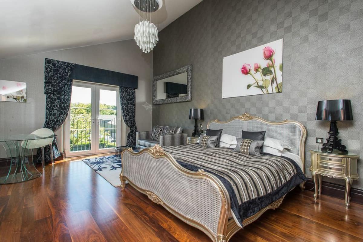 A spacious bedroom with a large bed, a glass table, and a view of the outdoors.
