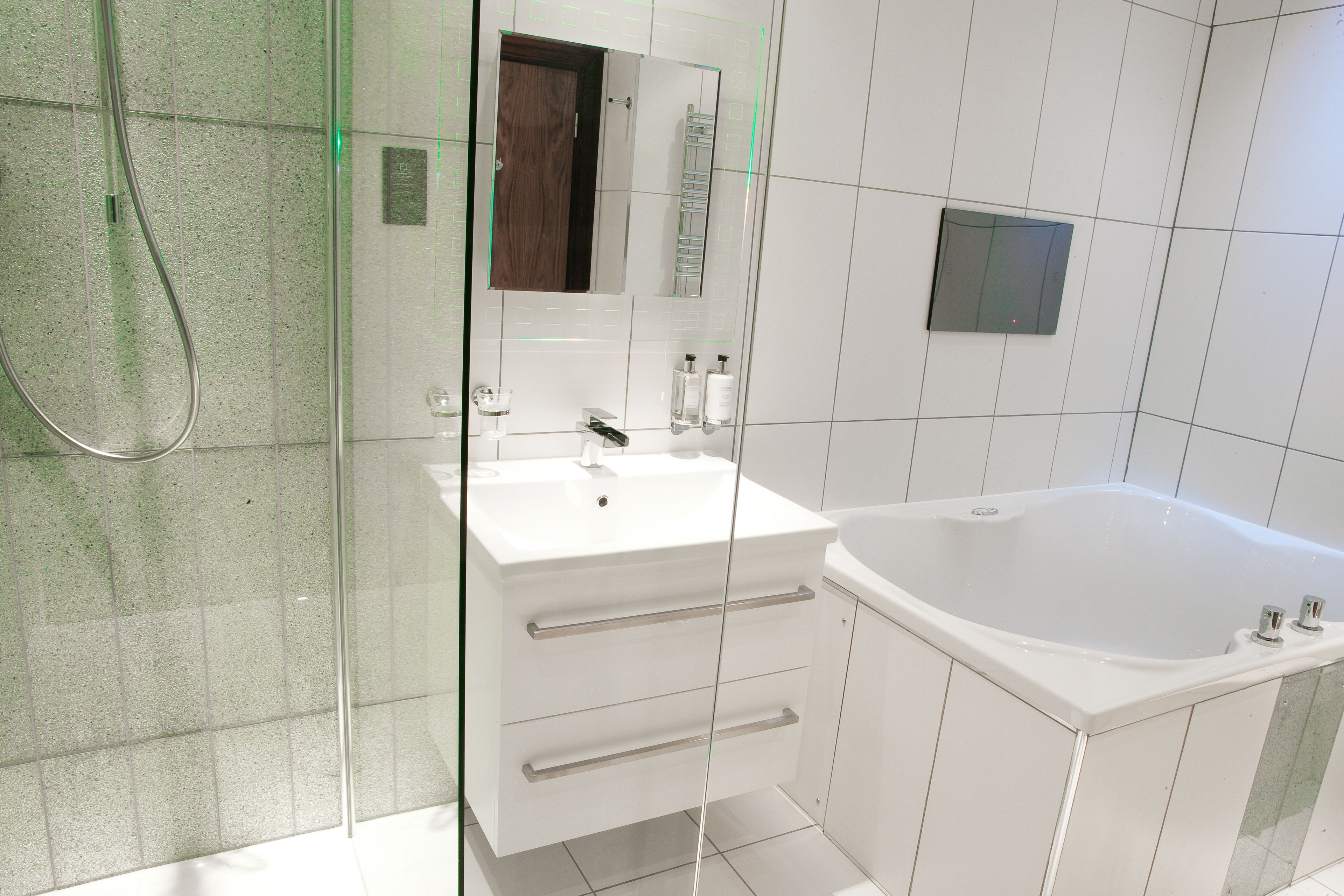 A modern bathroom with a glass shower enclosure, a white sink with a mirror, and a freestanding bathtub.