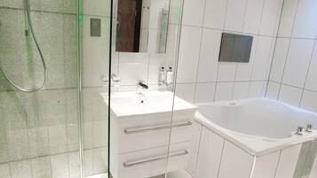 A modern bathroom with a glass shower enclosure, a white sink with a mirror, and a freestanding bathtub.
