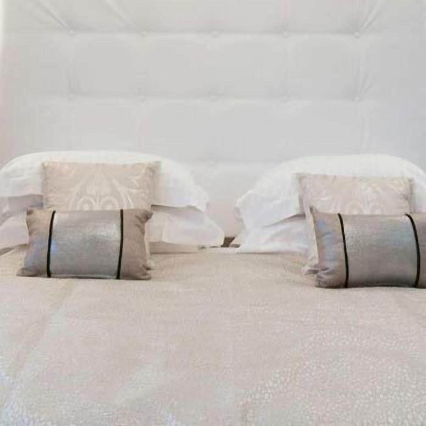 Camera d'albergo con due letti, entrambi con lenzuola bianche e cuscini decorativi.