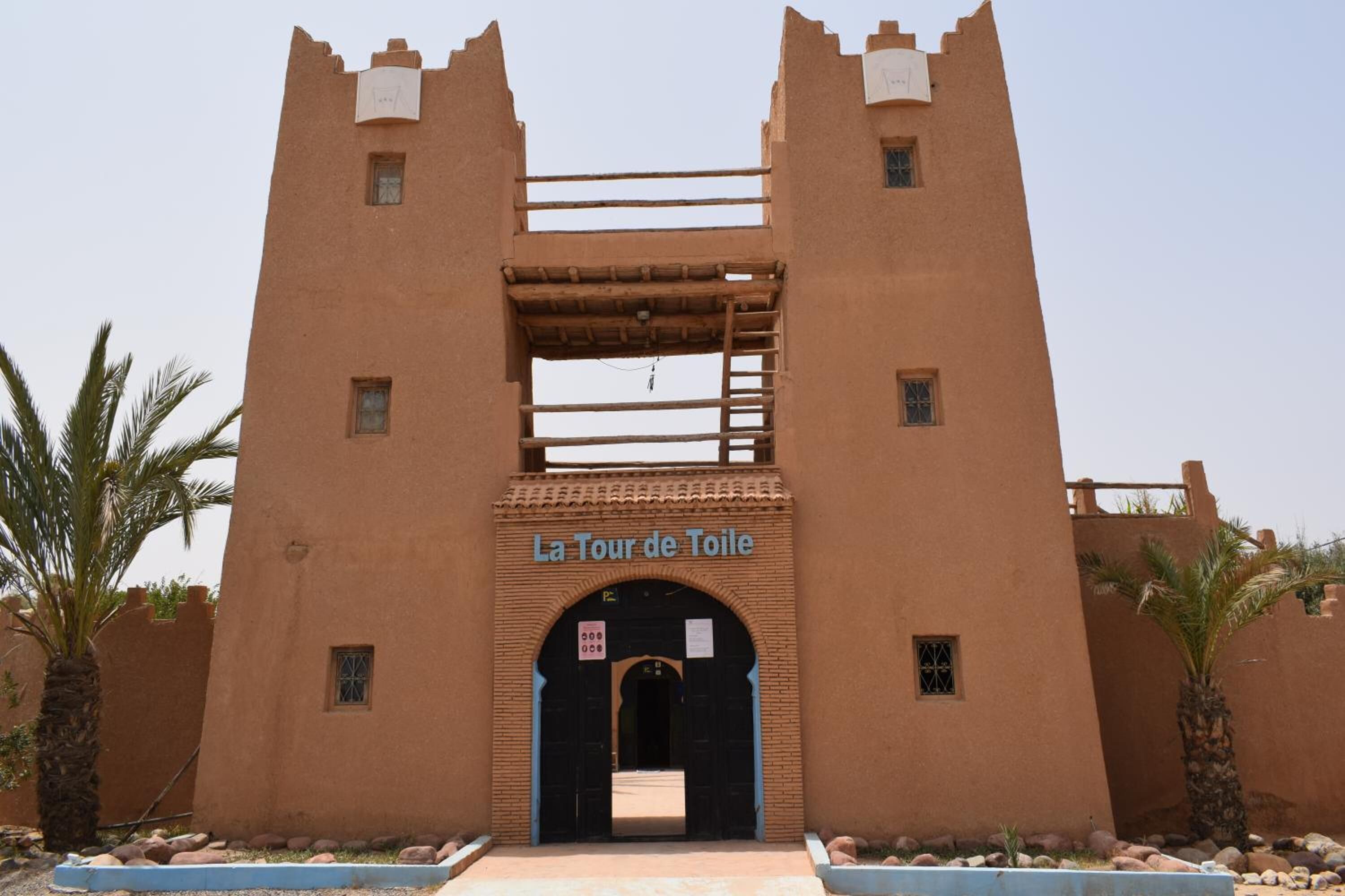 A building with a sign reading "La Tour de Toile" and a wooden ladder leading to an upper level.