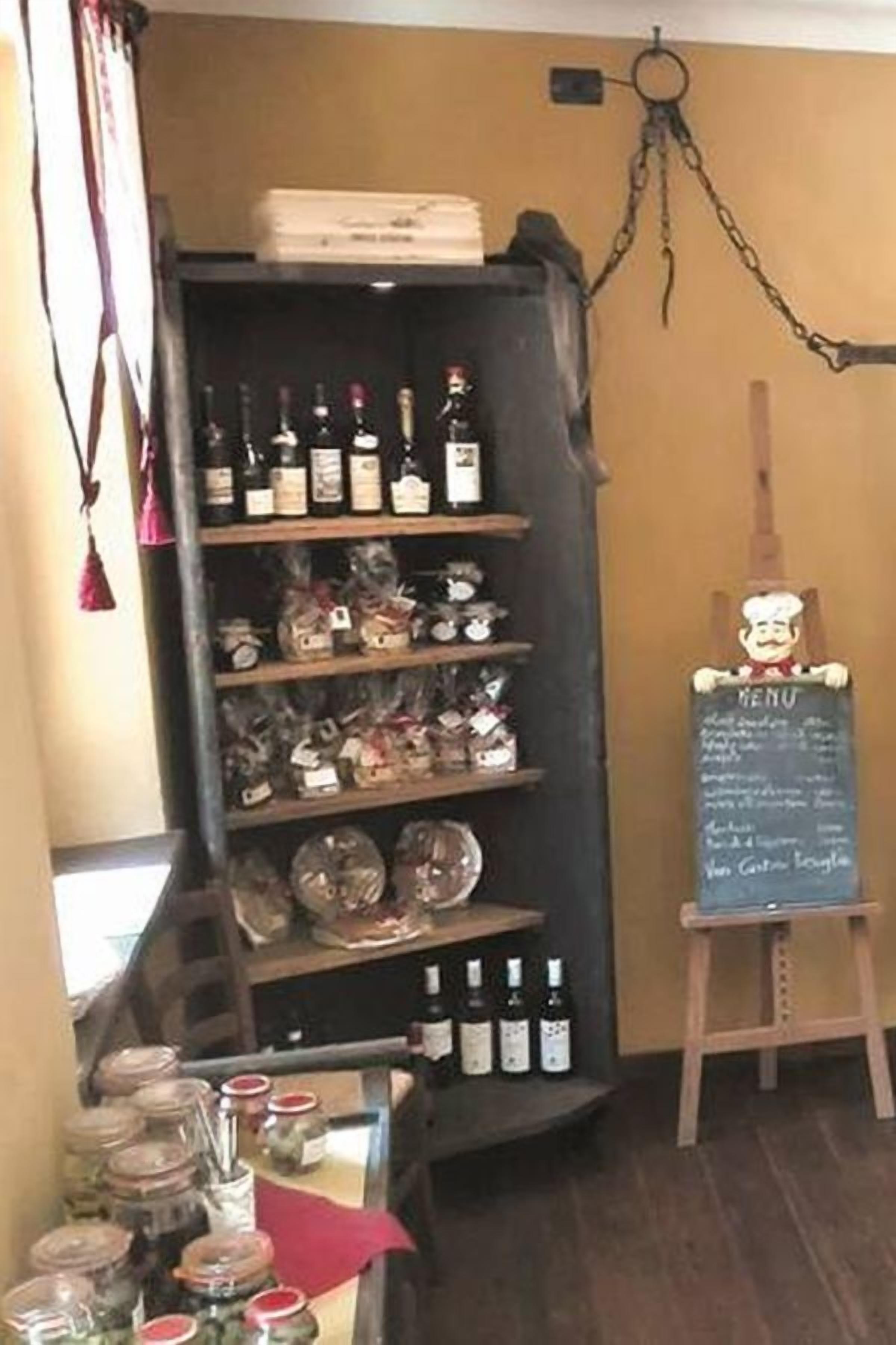 A restaurant interior with shelves of bottles and jars, a chalkboard menu, and a hanging chain.