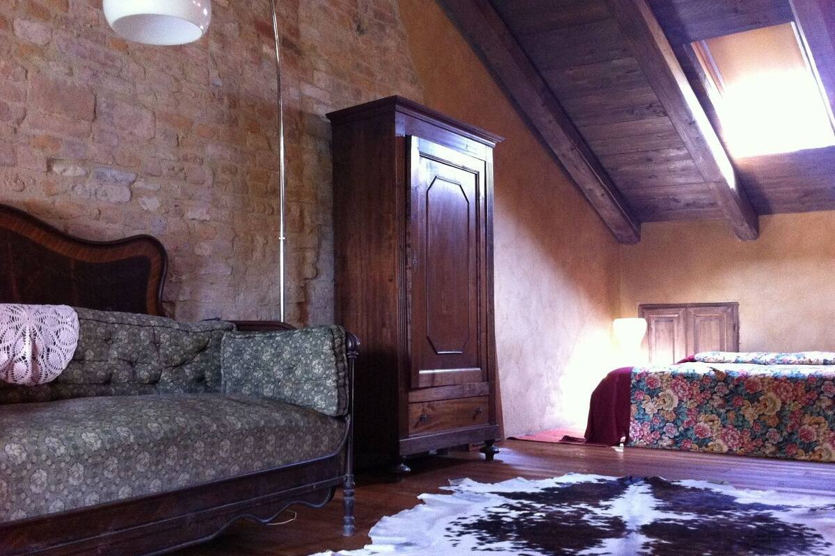 A rustic room with a wooden ceiling, a large cabinet, a sofa, and a bed with floral bedding.