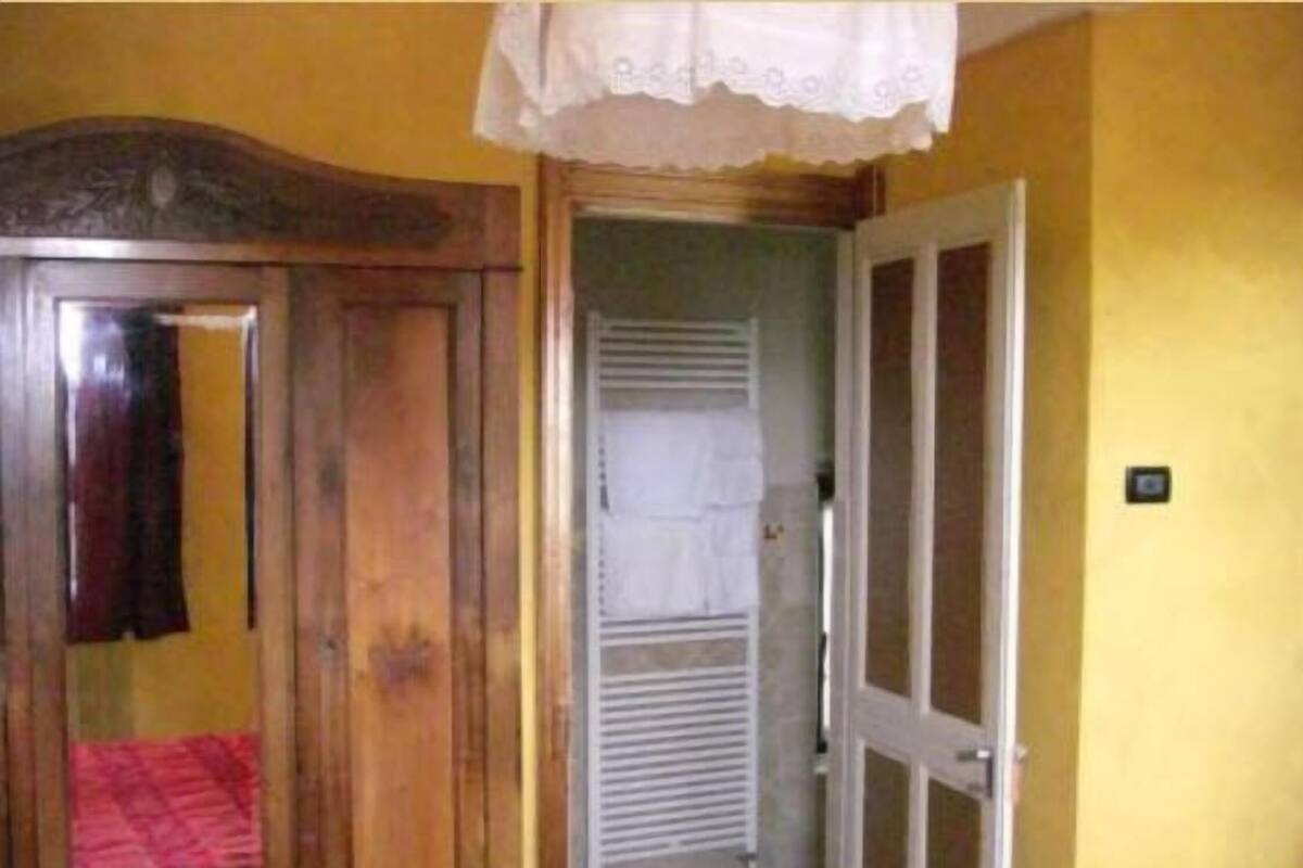 A room with a wooden wardrobe, a door with a white towel, and a light switch on the wall.