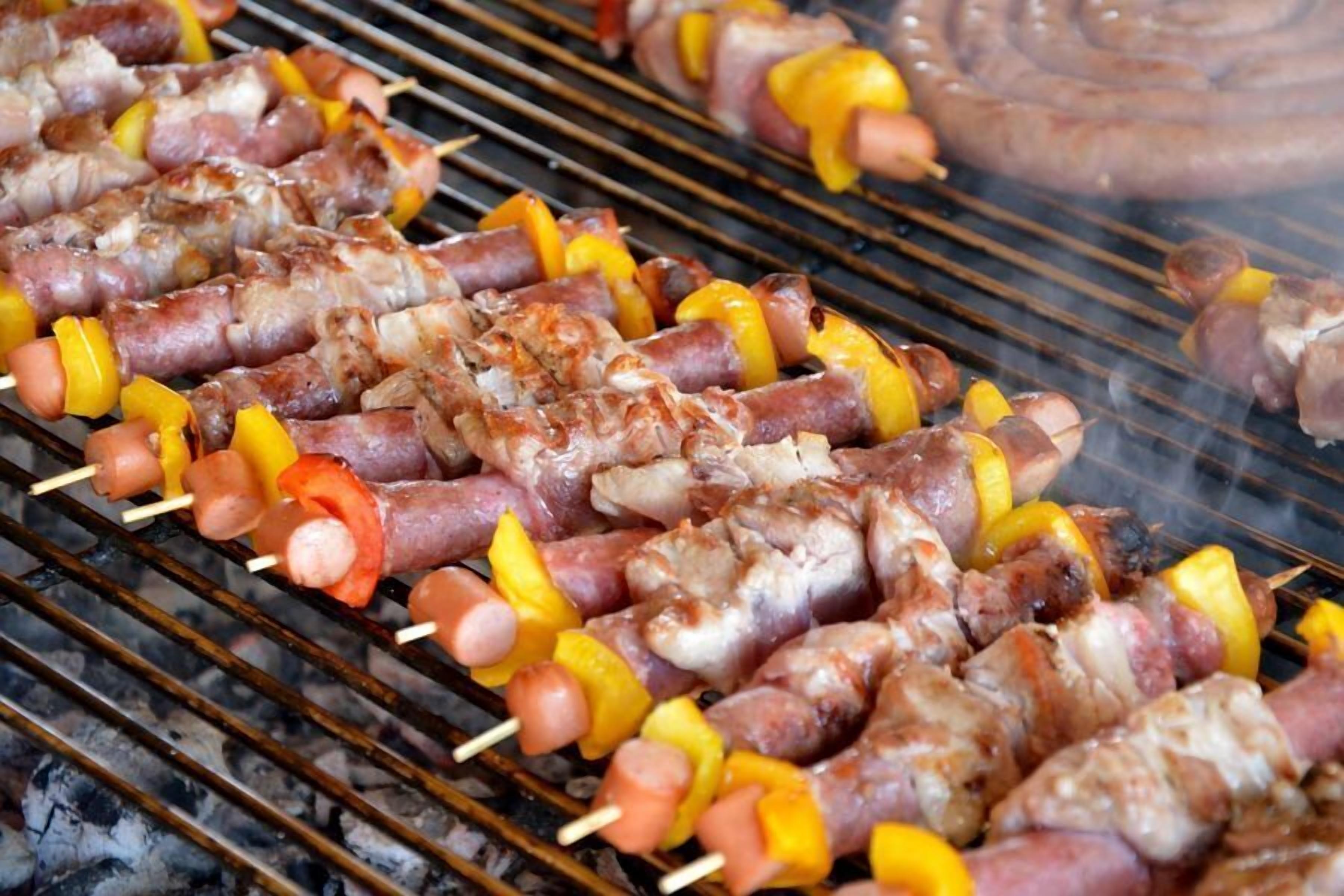 Brochetas de carne y verduras sobre una parrilla.