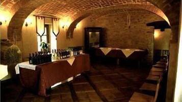 A wine cellar with wooden tables and bottles, arched brick ceilings, and a long bench along the wall.