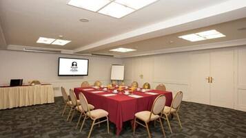 A conference room with a large table, chairs, a projector screen, and a whiteboard.