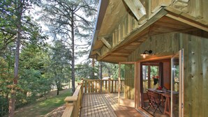A wooden deck with a table and chairs, surrounded by trees. - Albirondack Park Camping Lodge and Spa (Albi)