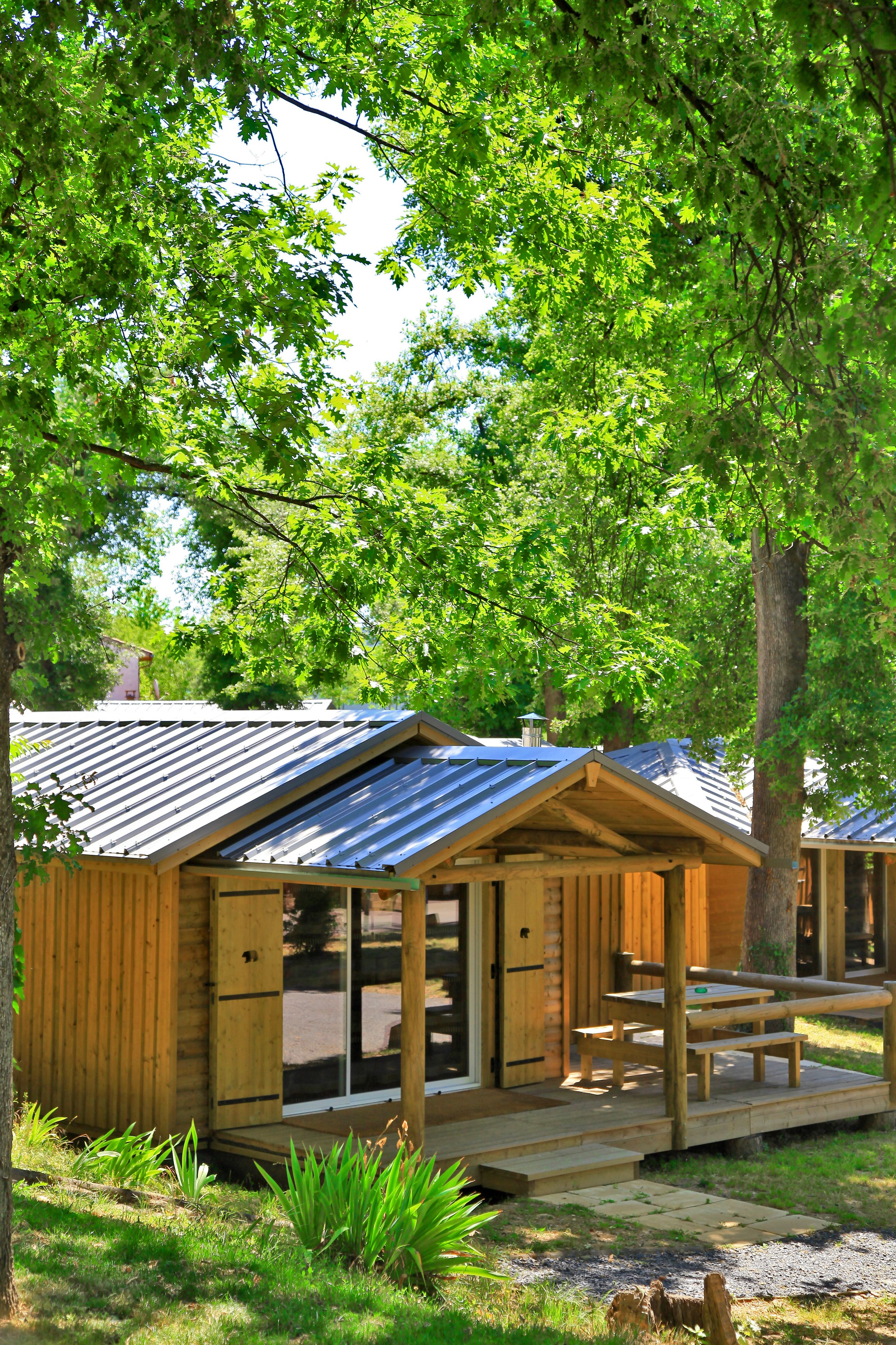 Une cabane en bois avec un toit en métal, une véranda et un banc.