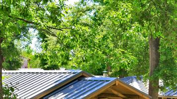 Une cabane en bois avec un toit en métal, une véranda et un banc.