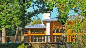 A modern building with a stone wall and wooden fence. - Albirondack Park Camping Lodge and Spa (Albi)