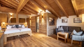 A wooden cabin interior with a bed, sofa, and a small table. - Hanusel Hof (Weitnau)