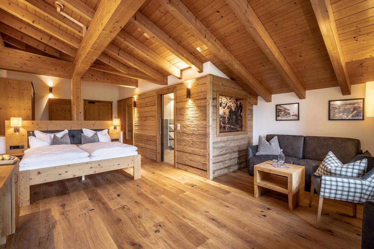 Interior de una cabaña de madera con una cama, un sofá y una mesita.