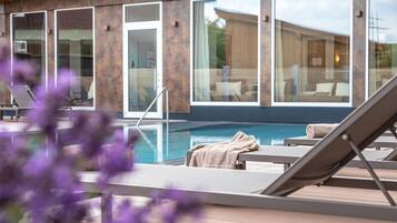 Zona junto a la piscina con sillas de descanso y vistas al agua.