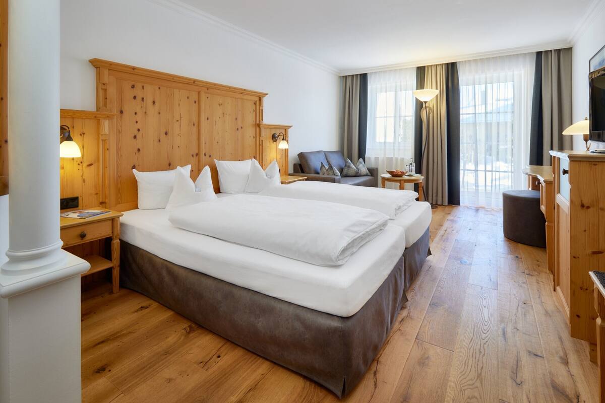 Habitación de hotel con una cama grande, un armario de madera, un escritorio y un televisor.