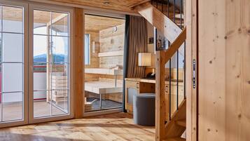 Interior de madera con una escalera, un escritorio y vistas a través de puertas de cristal.