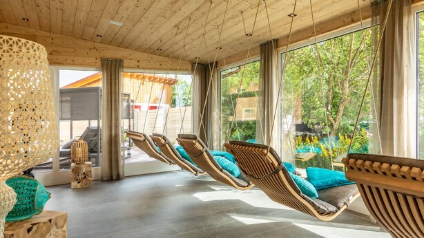 A sunroom with wooden ceiling, large windows, and three wicker loungers with cushions. - Hanusel Hof (Weitnau)