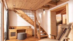A wooden interior with a wooden staircase, a cushioned chair, and a small kitchenette. - Hanusel Hof (Weitnau)