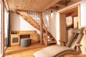 Un interior de madera con una escalera de madera, un sillón acolchado y una pequeña kitchenette.