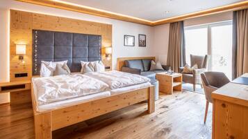 Een hotelkamer met een houten bed, een bureau, een stoel en een groot raam.