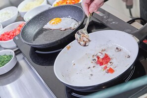 A kitchen with a frying pan on a stove, containing a fried egg and diced vegetables. - Weinhaus Halfenstube (Senheim)