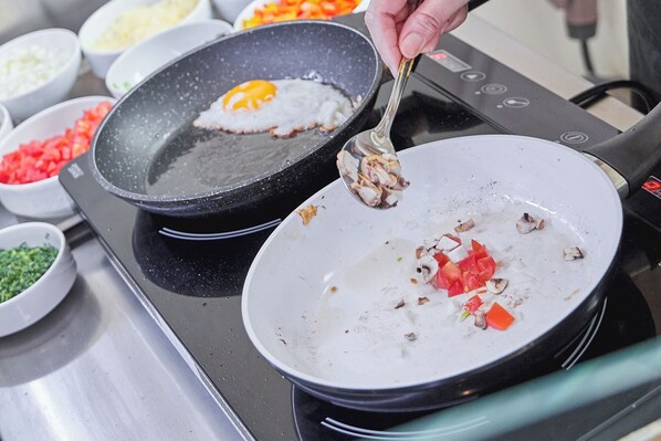 Una cocina con una sartén sobre la estufa, con un huevo frito y verduras picadas.