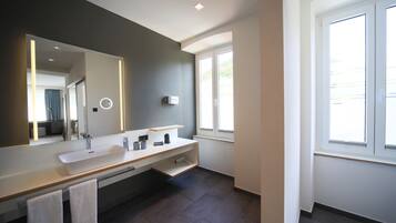 A modern bathroom with a large mirror, two sinks, and a window.