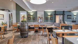 L’intérieur d’un restaurant avec des meubles en bois, un grand tonneau et un design moderne au plafond.