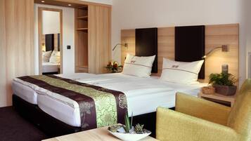 Una habitación de hotel con una cama grande, una mesita de noche con una planta, una silla y un armario.