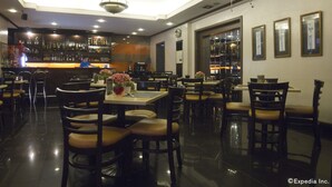 A restaurant with a bar area, multiple tables and chairs, and a polished floor. - Riviera Mansion Hotel (Manila)
