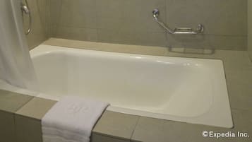Un baño con bañera, ducha y una pequeña ventana.