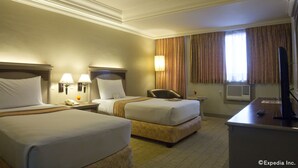 A hotel room with two beds, a desk with a computer, and a window with curtains. - Riviera Mansion Hotel (Manila)
