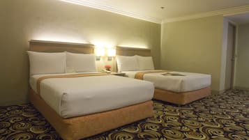 Une chambre d’hôtel avec deux lits, une moquette à motifs et une table de chevet avec une lampe.