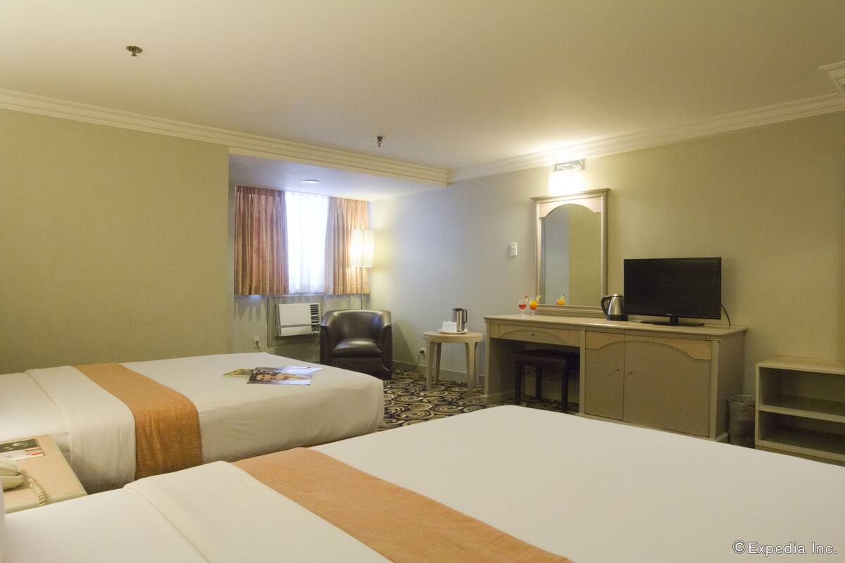 A hotel room with two beds, a desk, a chair, a television, and a mirror.